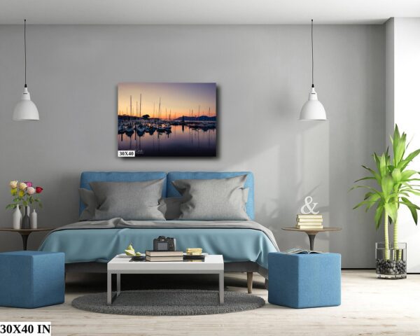 A bedroom with a blue bed and a painting of boats in the water.