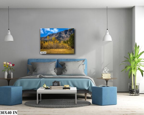 A bedroom with a blue bed and a painting on the wall.