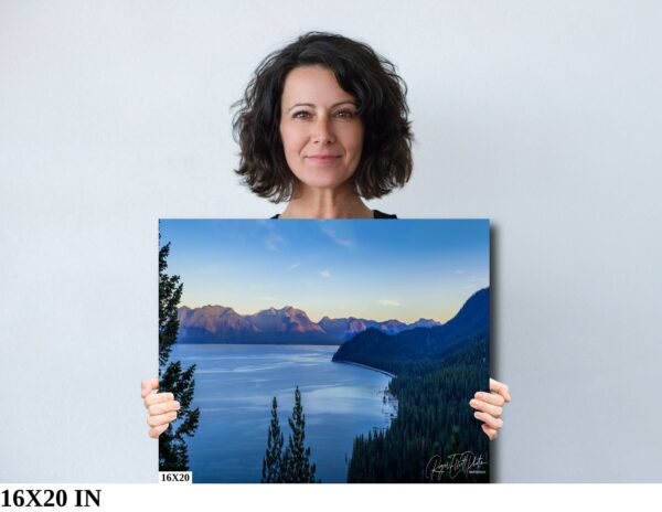 A woman holding up a painting of the ocean.