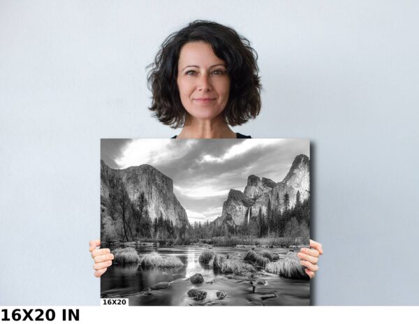 A woman holding up a picture of mountains and water.