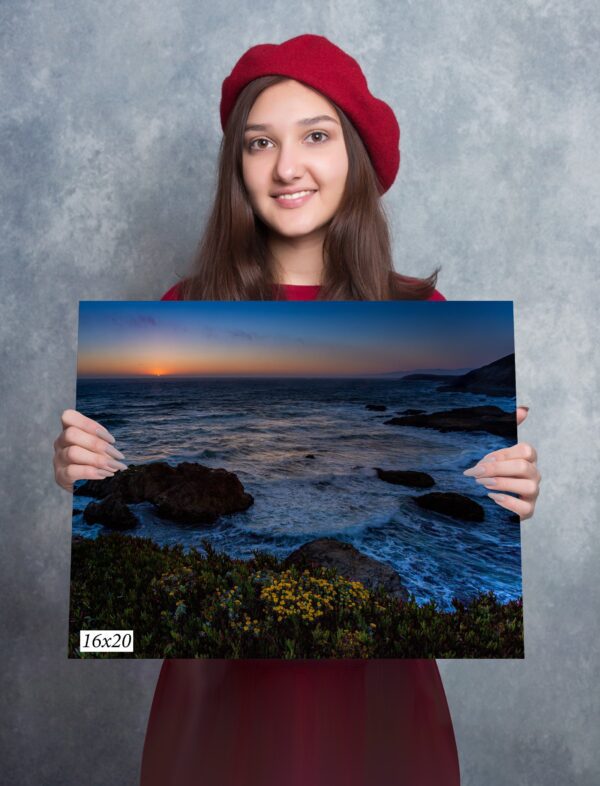 A girl holding up a picture of the ocean.