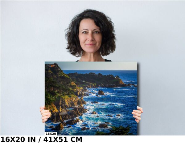 A woman holding up a large painting of the ocean.