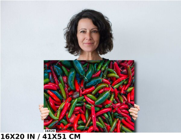 A woman holding up a picture of red and green peppers.