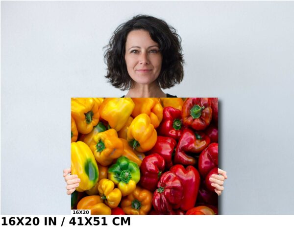 A woman holding up a painting of peppers.