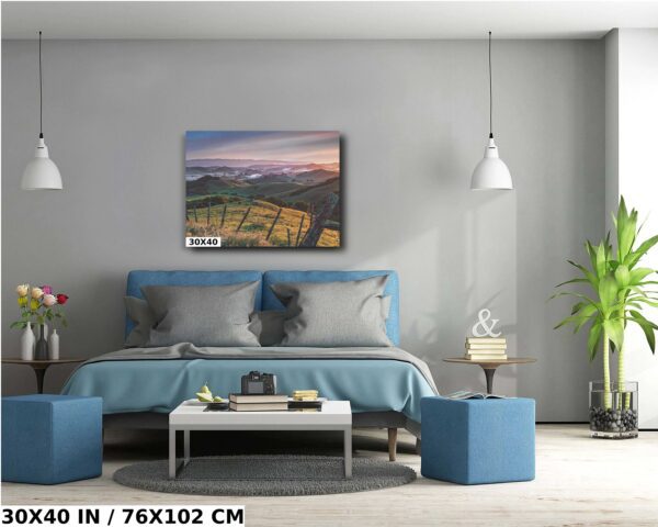 A bedroom with a blue bed and a painting of the mountains