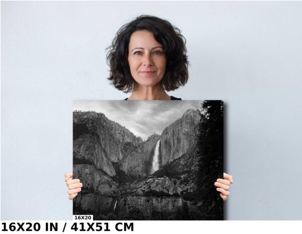 A woman holding up a picture of a waterfall.