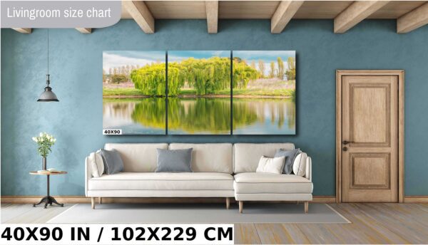 A large painting of trees and water in front of a wall.