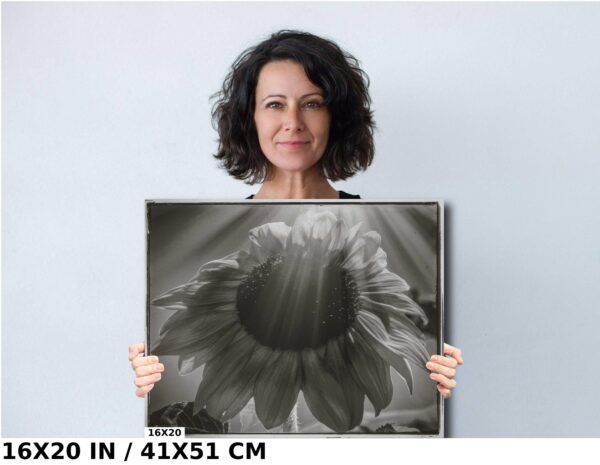 A woman holding up a large black and white photo.