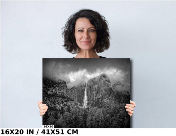 A woman holding up a picture of a waterfall.