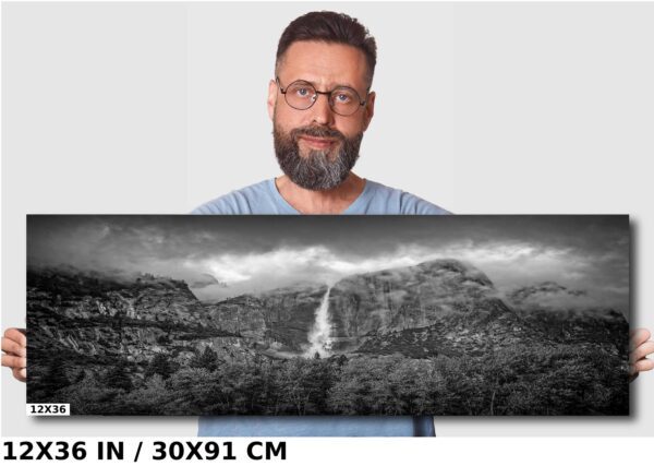 A man is holding up a large photo of a waterfall.
