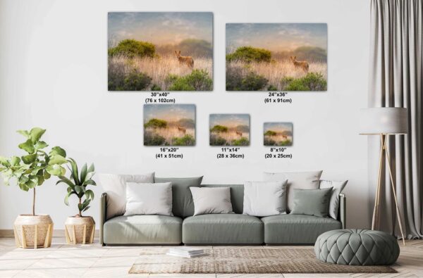 A couch with pillows and a painting of deer in the background.