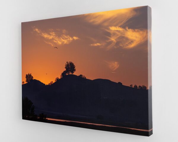 A sunset with clouds in the sky and trees.
