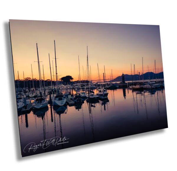 Sailboats docked in a marina at sunset with golden sky and calm water reflecting masts in Sausalito, California.