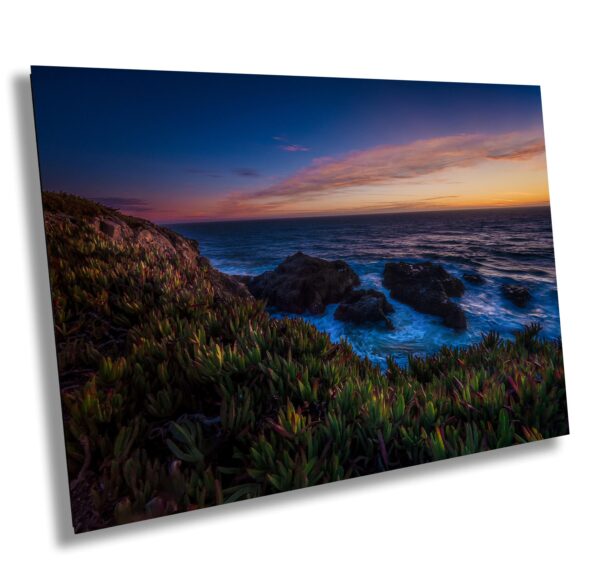 A picture of the ocean at sunset with grass on top.