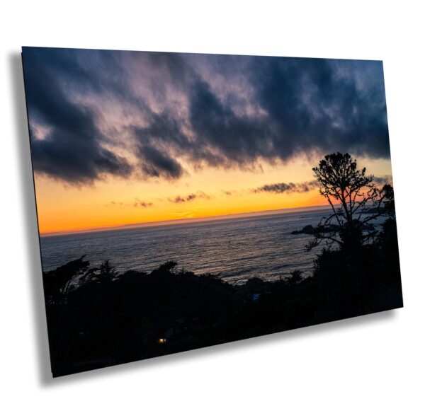 A sunset over the ocean with dark clouds in the sky.