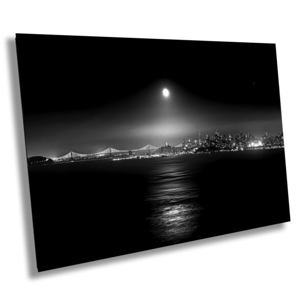 A black and white photo of the moon over water.