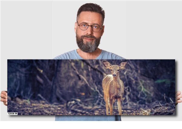 A man is standing in front of a picture of a deer.