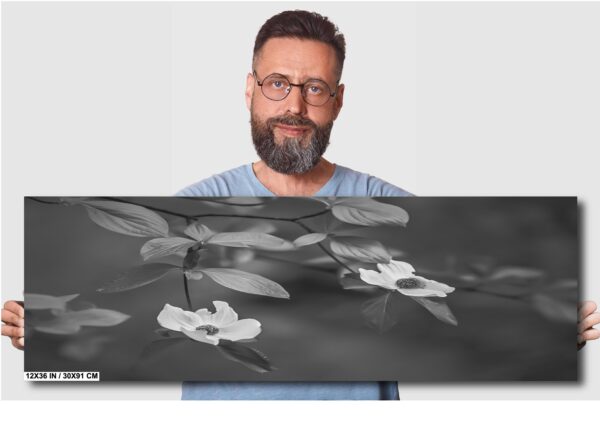 A man holding up a large painting of flowers.