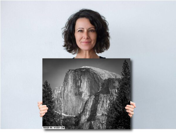 A woman holding up a picture of the side of a mountain.
