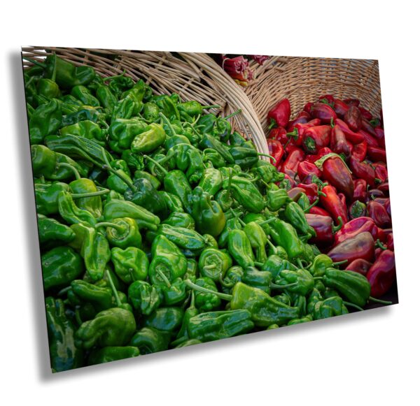 A basket of green peppers next to red peppers.