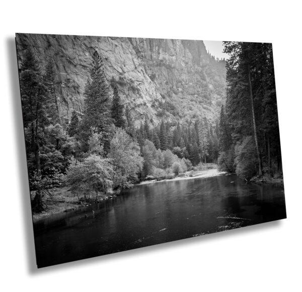 A black and white photo of the river in front of mountains.