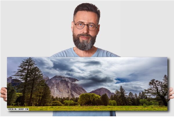 A man is holding up a picture of a mountain