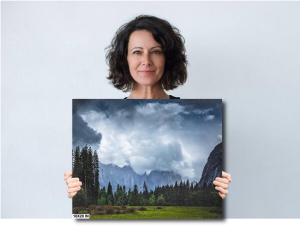 A woman holding up a picture of mountains and trees.