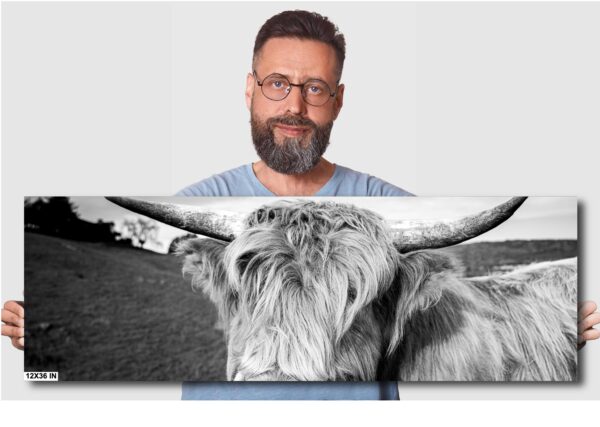 A man with glasses and beard standing next to an image of a bull.