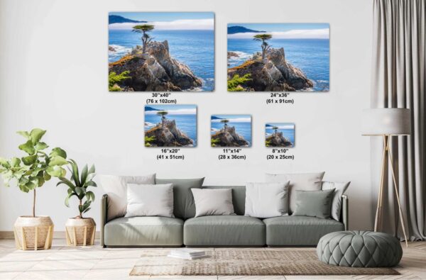 A living room with couch and pillows, two pictures of the ocean and a rock formation.