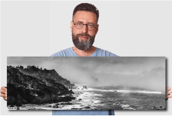 A man standing next to an ocean with waves crashing on it.