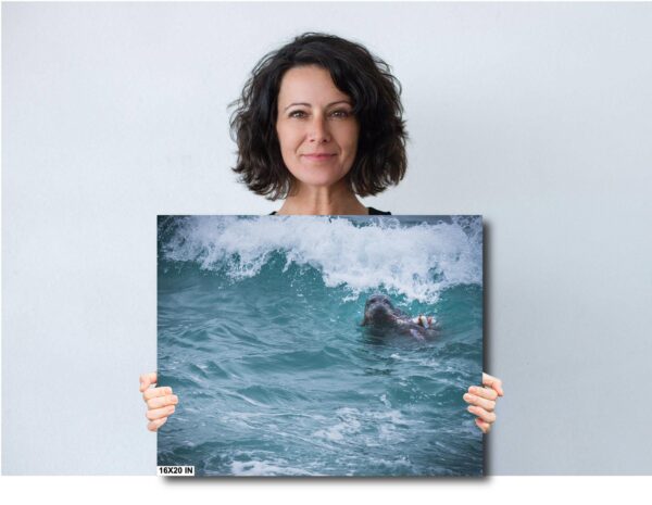 A woman holding up a picture of a surfer in the ocean.