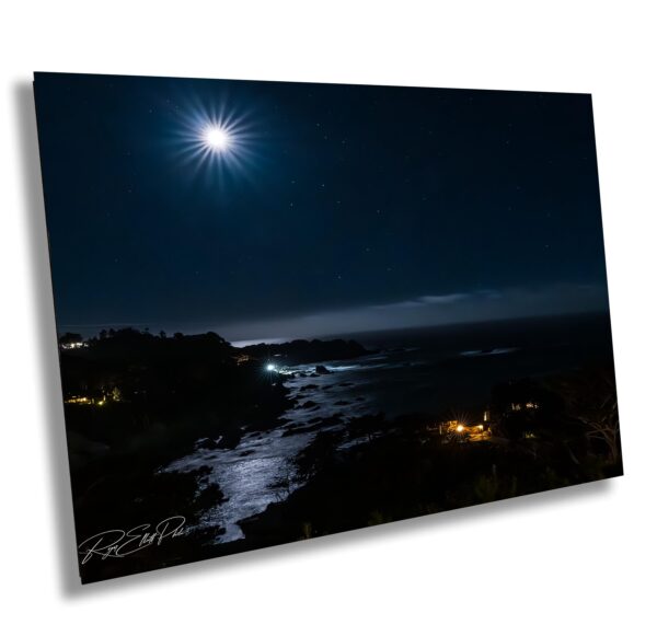 A full moon over the ocean at night.