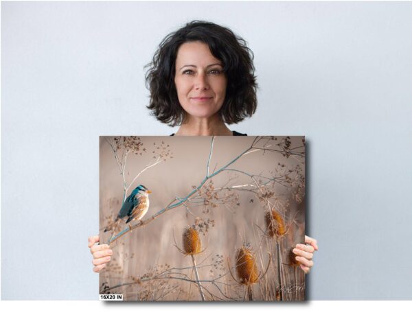 A woman holding up a painting of a bird.