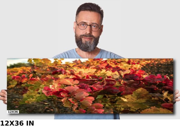 A man standing in front of a picture with autumn leaves.