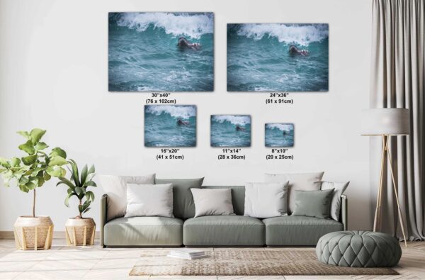 A living room with couch and pillows, and two pictures of surfers in the water.
