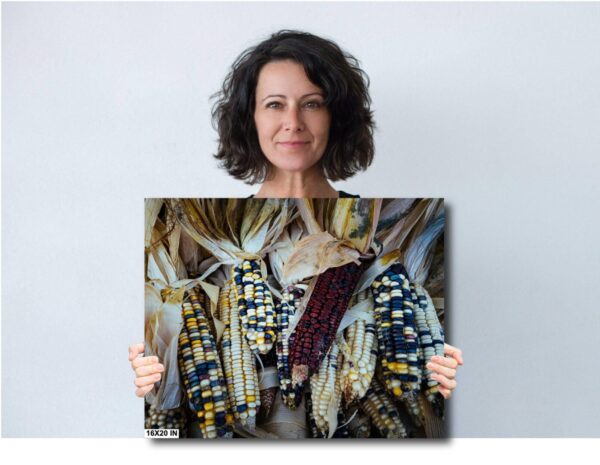 A woman holding up a painting of corn.