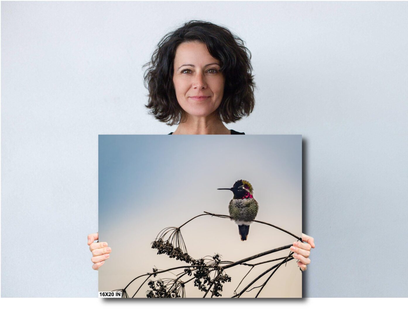 A woman holding up a picture of a hummingbird.