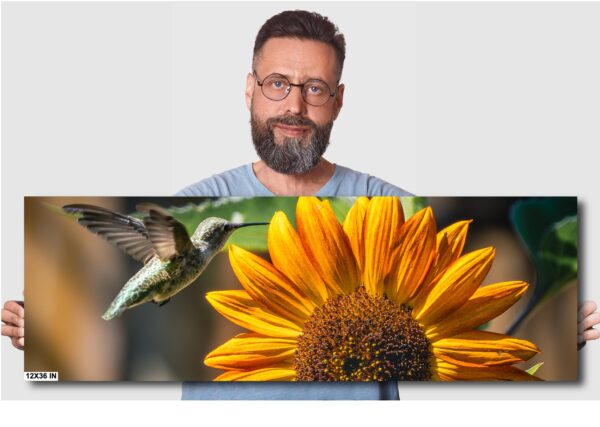 A man with glasses and beard standing next to a sunflower.