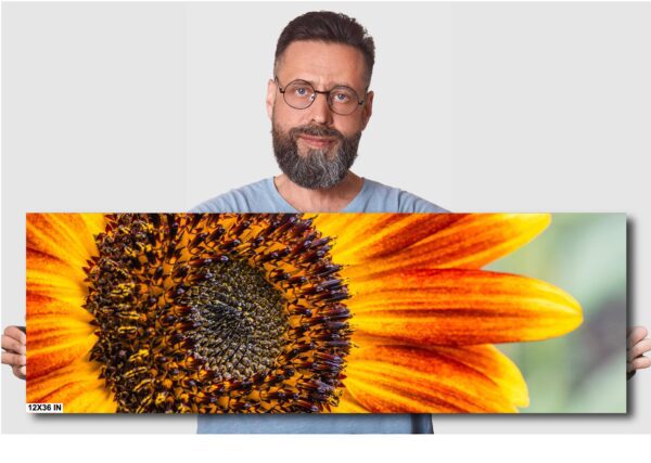 A man standing next to a sunflower with one eye open.