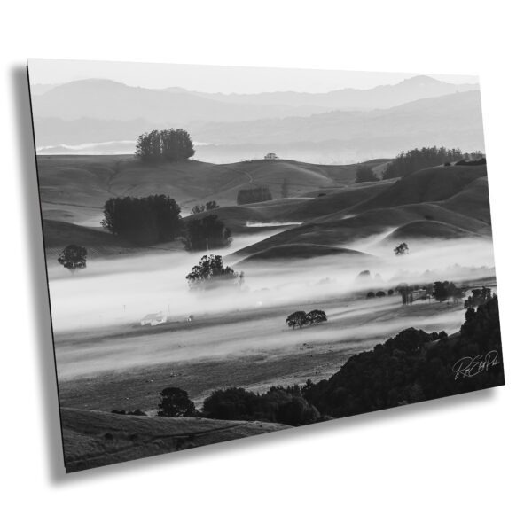 Black and white image of fog rolling over hills and a farmhouse in Sonoma County, California